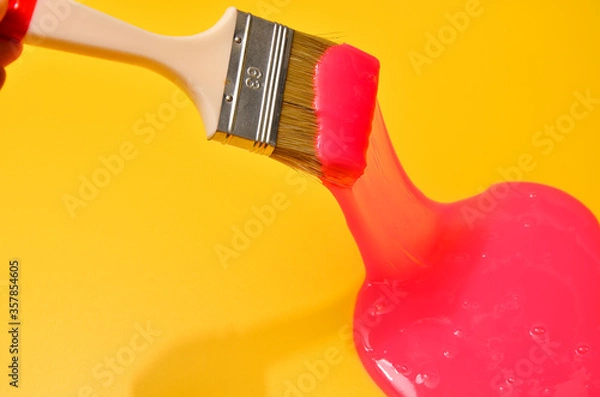 Fototapeta Shot of a brush with pink sticky slime on yellow background. Minimalism in photography, concept creative picture.