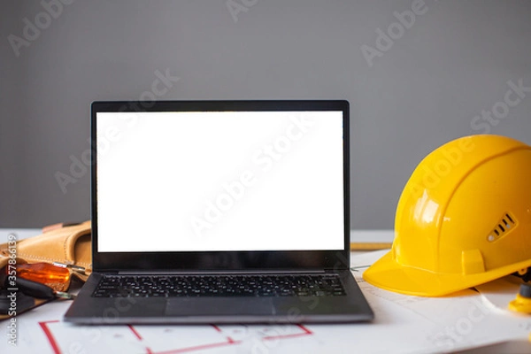 Fototapeta laptop and construction items, yellow helmet, apartment plan on the table, text, construction concept nobody