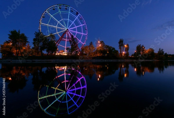 Fototapeta Colorfull abstract Ferris wheel with reflection on the Konny island in Irkutsk city