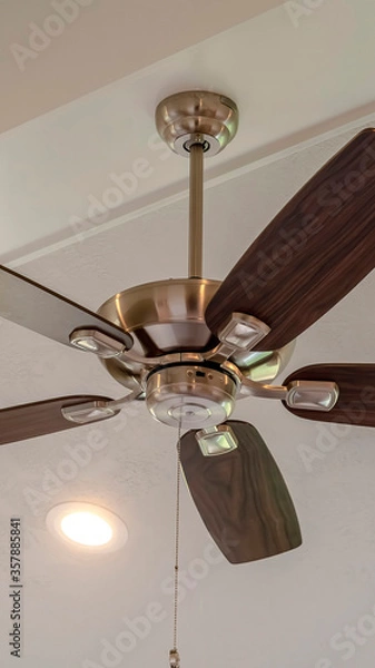 Obraz Vertical Electrical fan with built in lights installed on decorative wooden ceiling beam