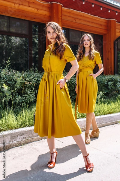 Obraz Two models on the street in mustard colored dresses