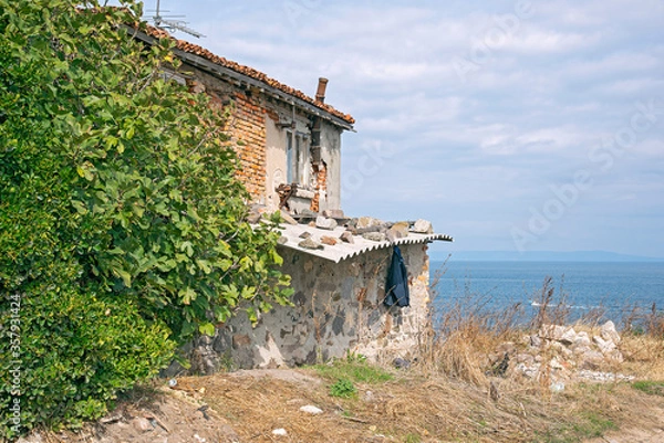 Obraz Fragments of old buildings against the backdrop of a cloudy summer sky and sea.