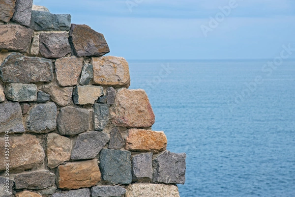 Obraz Fragments of old buildings against the backdrop of a cloudy summer sky and sea.