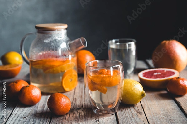 Fototapeta Citrus tea in a transparent teapot on a table with grapefruit and on a wooden table. Healthy drink.