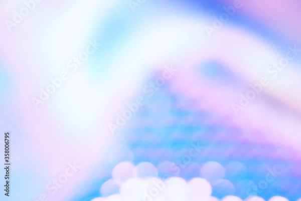 Fototapeta Holographic color foil with shiny reflections and bokeh light effect. Abstract blurred holographic foil background with trendy ultra violet light pastel colors.
