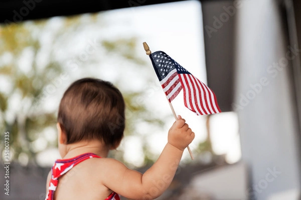 Obraz Baby girl celebrating  4th of July with USA flag in hand, Traditional American Holiday