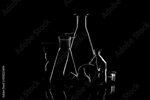 Fototapeta Low-key Studio Shot of a White silhouette of a chemical laboratory utensils light glasses isolated on a black Background. Smooth lines and shapes. .
