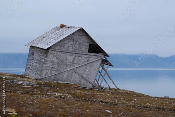 Fototapeta Crooked wooden cabin which is standing alone and abandoned in the tundra on Spitsbergen