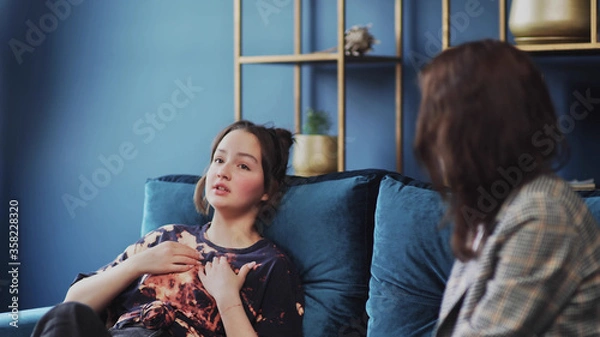 Fototapeta Teen with pain. A teen with pain and problems sits on the sofa and speak with psychologist.