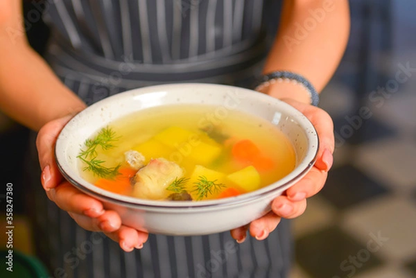 Fototapeta A waiter wearing black uniform serving a bowl of hot soup in a restaurant. Concept for a tasty and healthy meal.