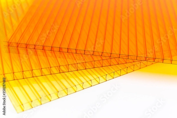 Fototapeta Polycarbonate plastic sheets panels images. PC hollow sheet for translucent roofing close up. Yellow, orange colors on white background