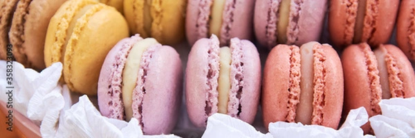 Fototapeta Multi-colored macaroons stacked in a row. Delicious French dessert Macaroon - a small cake or complex cookies made from chopped almonds and meringues. Selective focus. close-up