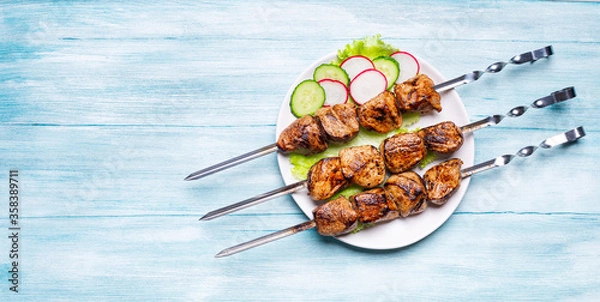 Fototapeta Cooked meat on skewers on a wooden background. Barbecue concept. top view
