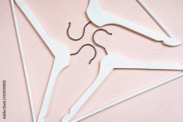 Fototapeta Top view of white wooden hangers on a pink background. The concept of the crisis of the fashion industry, the closure of shops. The trend of conscious consumption, eco-friendly anti-consumerism. 