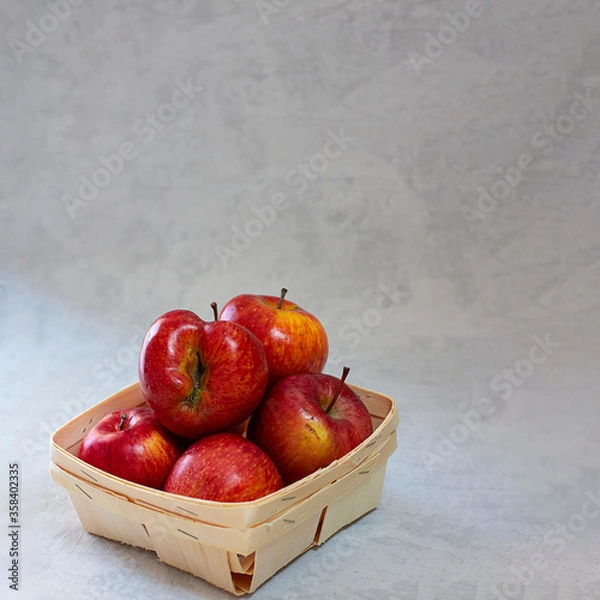 Fototapeta Red fresh organic apples in small wooden pottle with ugly fruit on top. On grey cement background with copy space. Buying imperfect product to reduce waste. Sustainable consumption. Square. Eco trend.