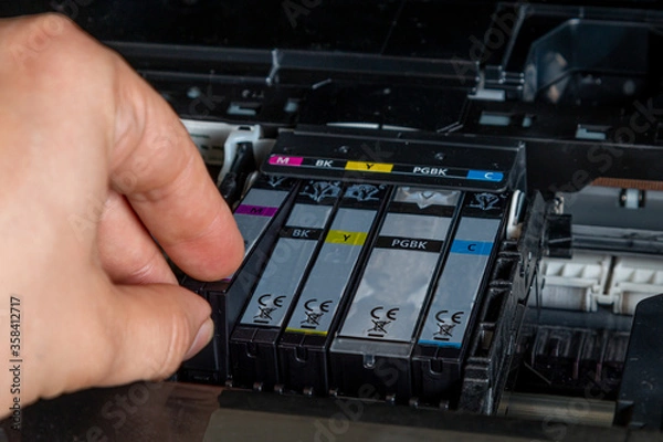 Fototapeta The man changes the ink for the printer