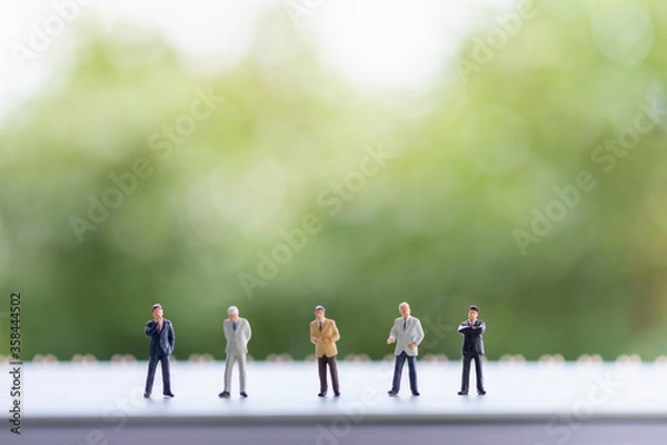 Fototapeta Miniature people: Business man stand on the book with copy space for text using as background saving, investment, money, financial, business analytics concept.