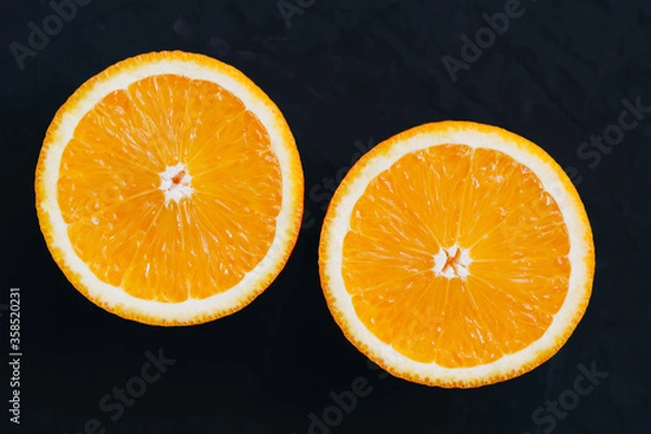 Fototapeta Top view on orange slices on black background.
