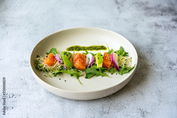 Fototapeta avocado, smoked salmon and cucumber salad on white plate