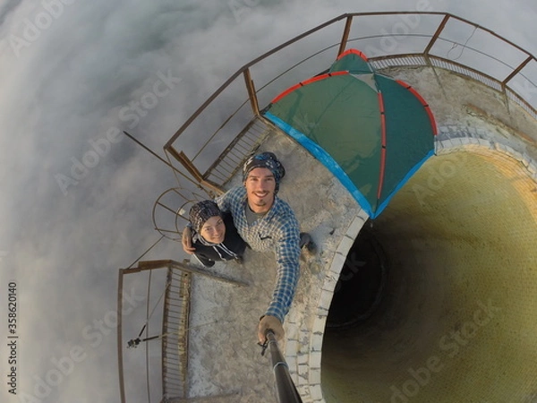 Fototapeta Camping on top of a smoke stack chimney, surrounded by fog and mist underneath the top of the building, sunrise