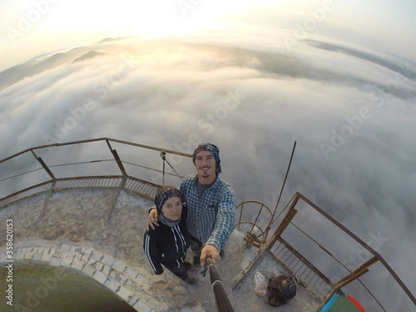 Fototapeta Camping on top of a smoke stack chimney, surrounded by fog and mist underneath the top of the building, sunrise