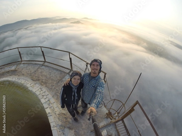 Fototapeta Camping on top of a smoke stack chimney, surrounded by fog and mist underneath the top of the building, sunrise