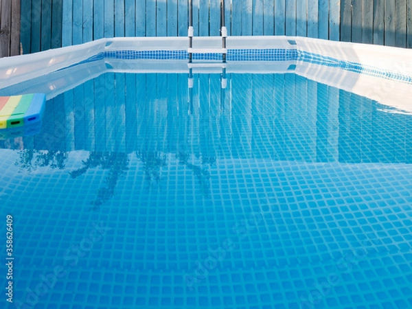 Fototapeta latest modern model of frame pool for children and adults in country house on flat concrete plot on gray background. Sunny summer day. concept of family holidays and active lifestyles after quarantine
