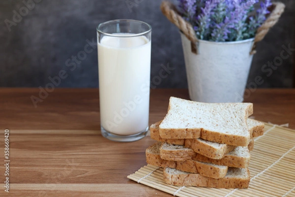 Obraz Whole Wheat Sliced Bread with milk on wooden table.