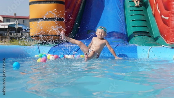 Obraz Child jump on inflatable water slide. Aqua amusement park of sea resort.