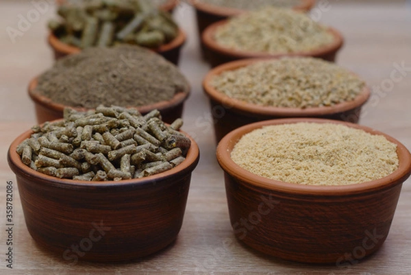 Obraz Different kinds of pelleted compound feed in bowls on wood table, copy space