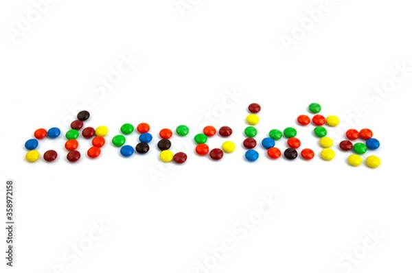 Fototapeta Colorful chocolate M&Ms in and out of focus on white background.