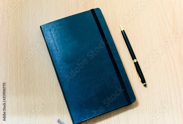 Fototapeta a note book and a black pen on an office table