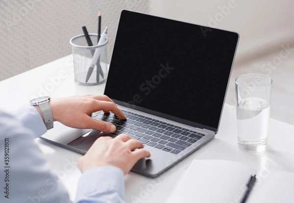 Obraz Work online remotely. Businessman uses laptop from blank screen