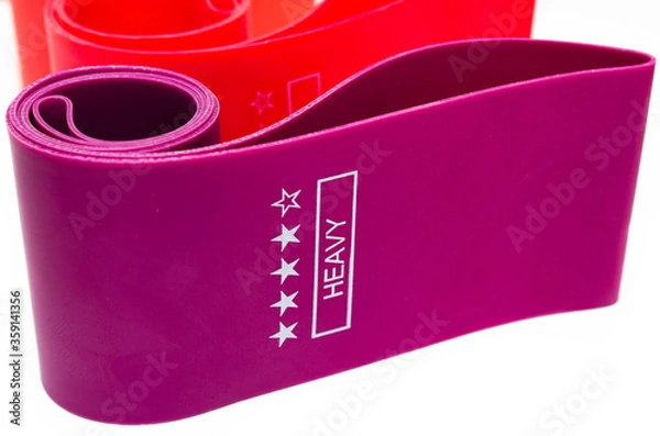 Fototapeta Elastic bands for fitness. Three elastic bands for fitness in close-up on a white background. Erasers lie on the table top and side view. A bunch of rezhinki, twisted into a roll. Elastic bands left 