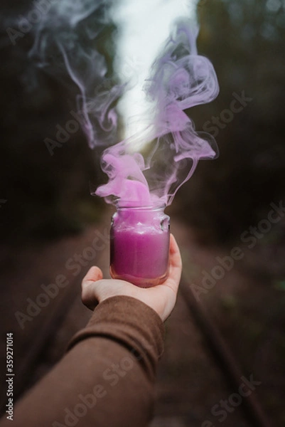 Fototapeta Pink colour smoke from a cup holded by a man hand on a forest