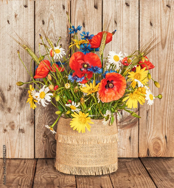 Fototapeta A Bouquet of Wild Flowers in a Vase on a Rustic Background. Vintage scenery.
