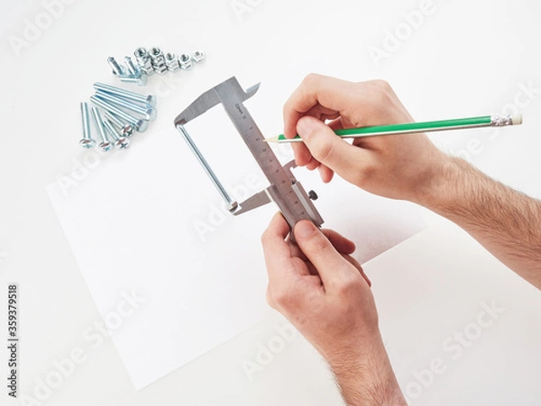 Fototapeta hands with a caliper measure bolts and nuts. on white background
