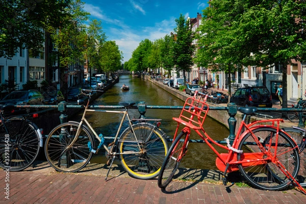 Fototapeta Amsterdam canal with boats and bicycles on a bridge