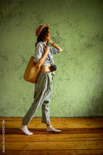 Obraz Tourist in a denim jacket and hat with a camera and bag. Happy emotions