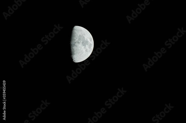 Fototapeta Shining half moon close up view, rising in a dark sky.