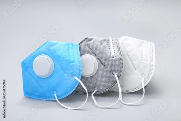 Fototapeta Three different coloured N95 masks with breathing valves on a white background.