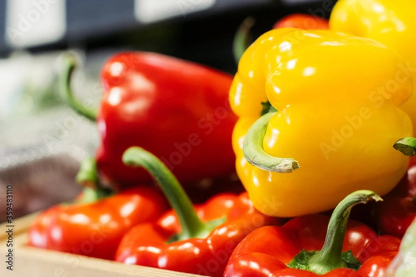 Fototapeta Side view of yellow bell pepper lying on red peppers on the shelf. Close-up of fresh agricultural vegetables in grocery. Vegeterian food, dieting, healthy eating.
