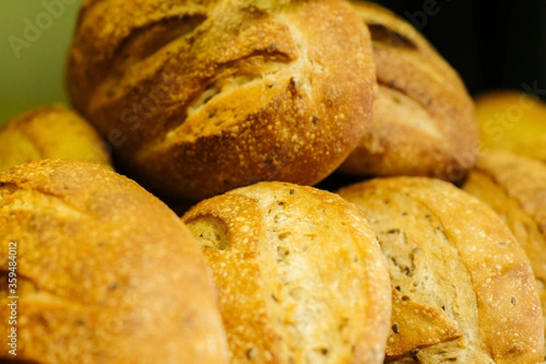 Fototapeta Fresh baked loaves of bread lying on the shelf in grocery store. Flavorful bakery in supermarket. Retail shop, food.