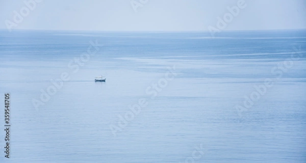 Fototapeta Small calm boat in the middle of the serene sea