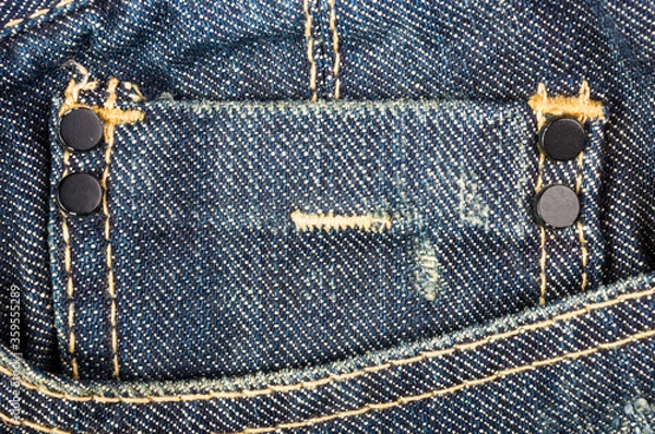 Fototapeta clothing items blue stonewashed faded jeans cotton fabric texture with seams, clasps, buttons and rivets, macro, close-up