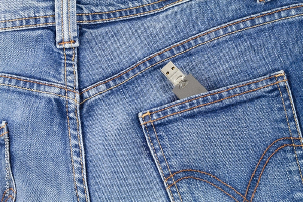 Fototapeta Flash USB drive memory coming out of jeans pocket