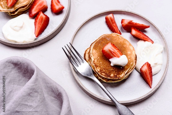 Fototapeta Homemade pancakes with strawberry and whipped cream (chantilly) on grey concrete background. Selective focus