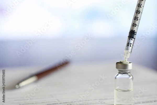 Obraz A man signs a medical document. Medical equipment on the table. Stethoscope and ampoules with syringes. Makes notes in the office. Medical center.