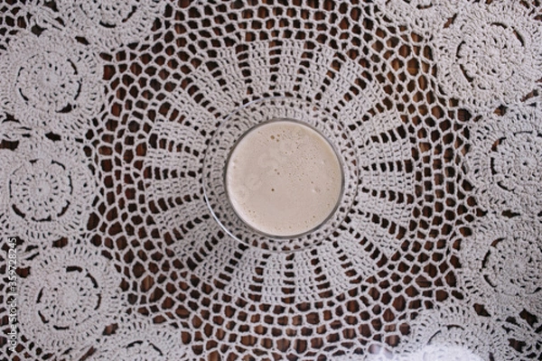 Fototapeta Latte coffee on the table with knitted white napkin on the cafe. Place for text