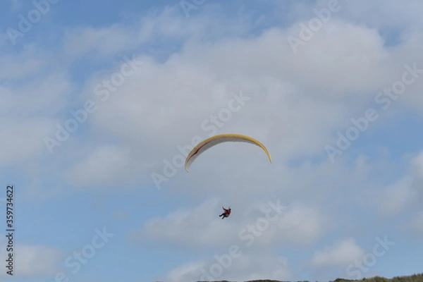 Fototapeta Paragliding at the beach of Katwijk aan Zee. Paraglider's making use of updraft of the dunes to stay in the air 